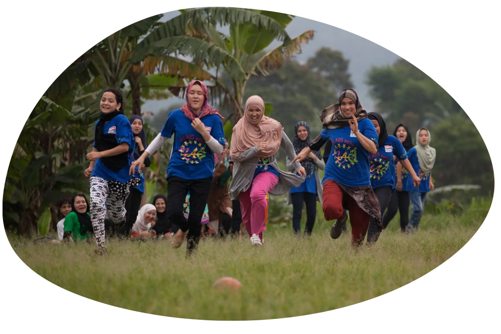 A group of people running towards the camera on grass.