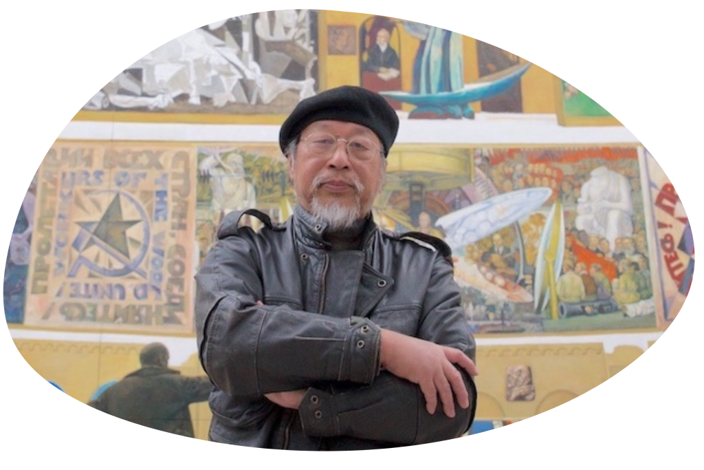 A picture of a man in front of some artworks from the documentary Welcome to Babel.